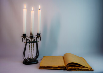 Vintage candelabrum with burning candles and an old open book