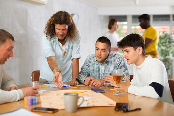 Group of active men play board games during a friendly meeting