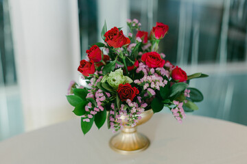 Vibrant floral arrangement featuring red roses and purple accents at a decorative display