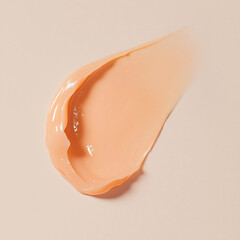 Peach or orange cream, moisturizer, hair mask or body butter with a smooth, creamy texture on a soft beige background.