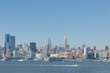 Obraz premium Iconic Manhattan skyline with the Empire State Building under clear blue skies during daytime