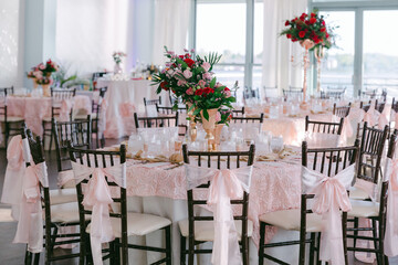 Elegant dining setup with floral centerpieces in a bright venue overlooking water