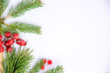 A festive arrangement of pine branches and red berries against a simple white background for...