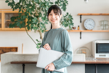 ノートパソコンを持つおしゃれな女性・オフィスカジュアル・デザイナー・ビジネスウーマン

