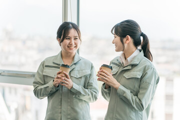 工場・中小企業で休憩・会話するエンジニア・作業員の女性従業員
