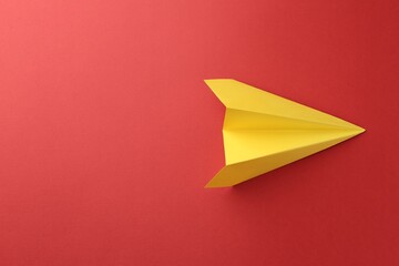 One handmade yellow paper plane on red background, top view. Space for text