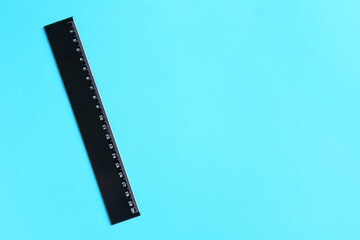 One black ruler on light blue background, top view. Space for text