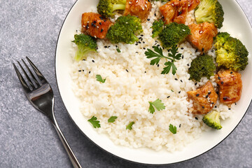 Tasty rice with broccoli, chicken and parsley on grey table, top view