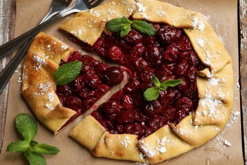 Tasty galette with cherries and mint served on table