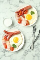 Tasty brunch. Fried eggs, sausage, bacon and tomatoes served on white marble table, flat lay