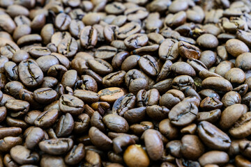 A close up of coffee beans with a lot of them in the foreground