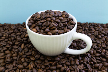 A white coffee cup is filled with coffee beans