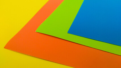 Vibrant colored paper sheets in blue, yellow, orange, green, and white. Perfect for design backgrounds, craft projects, and creative visual compositions