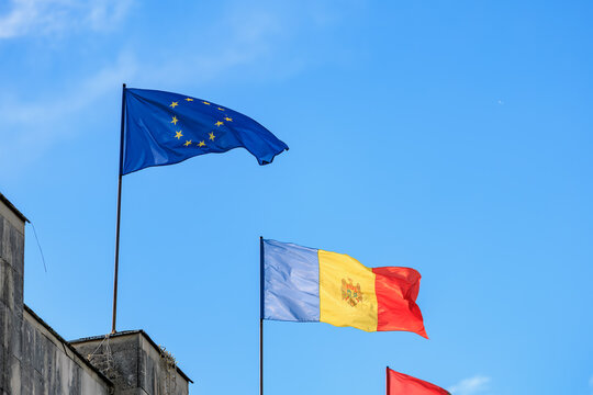 European union and moldovan flags waving against clear blue sky
