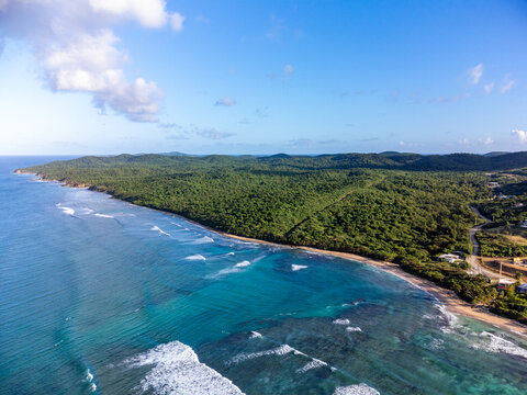 Aerial view of Vieques, Puerto Rico with its lush forests, beaches, and turquoise blue waves crashing onto coral reefs.