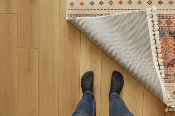 Feet standing on floor as a rug is pulled back in a home setting