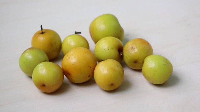Fresh plum fruits rest on a light wooden surface. These are called Boroi or Kul in Bangladesh and are also known as Indian jujube, Chinese date, or Chinee apple.