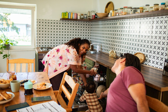 Happy family unloading dishwasher together in cozy kitchen - Powered by Adobe