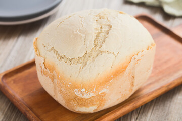 Fresh homemade loaf of white bread made by a bread making machine, served on wooden board...
