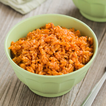 Homemade Mexican red rice or Arroz rojo made with onion, garlic and tomato or tomato paste or sauce, a traditional Mexican side dish, served in green bowl (Selective Focus)