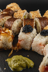 Sushi platter featuring various rolls with wasabi and caviar on black slate