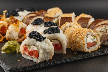 Exquisite sushi rolls displayed on a dark stone platter with elegant garnishes