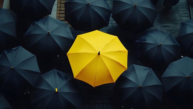 Single yellow umbrella amidst many black umbrellas on city street