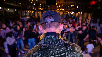 DJ Plays to Energetic Crowd at Outdoor Music Festival Under Bokeh Lights