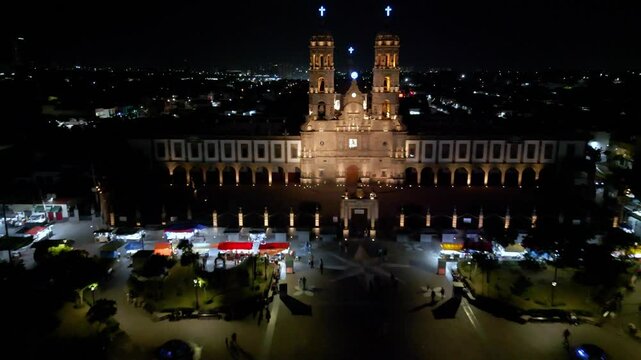 Aerial night shot moving forward toward the illuminated Basilica of Our Lady of Zapopan, capturing its architectural details