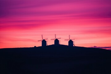 Windmills stand tall against the vibrant sunset, a symbol of heritage, travel, and peace