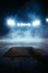 A wide-angle view of an empty baseball stadium at night, illuminated by bright lights. The background is dark and moody with subtle smoke effects