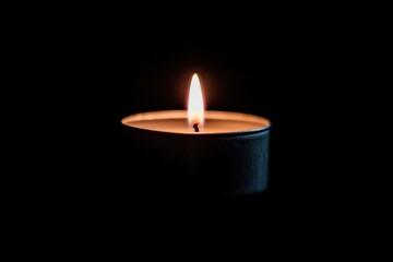 Candle flame burning bright in the dark room creating warm light and simple scene