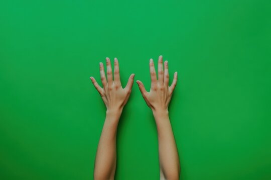 Two hands reaching upward against a bright green background - Powered by Adobe