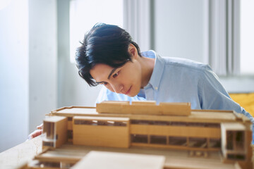 工学部のある大学で真剣な表情で建築模型を作る1人の男性の建築学科の学生