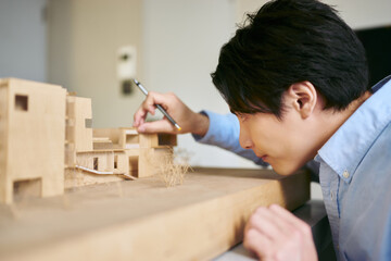 設計のコンペディションの為の建築模型を真剣に想像力を働かせて作る1人の男性