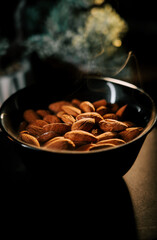 Elegant bowl of roasted almonds on a dark surface with a backdrop of smoky atmosphere