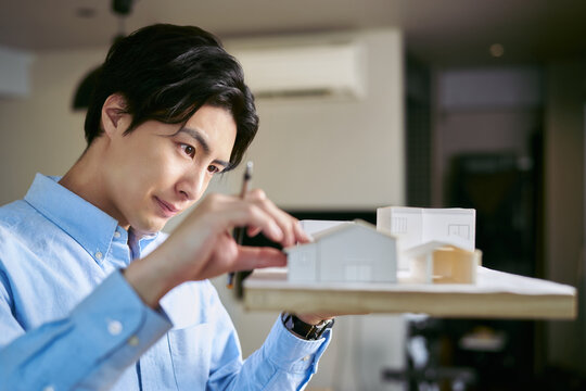 事務所で建物の模型を作って住環境を考えた建築を設計する建築家の男性
