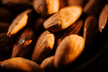 Almonds arranged on a plate against a black background showcasing their natural texture and color