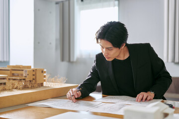 建築模型を横に大規模な建物の設計をする設計事務所で仕事をする1人の男性