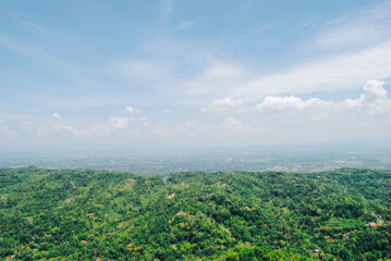 Fototapeta premium Top view of mountains with green forest landscape on a sunny day with blue sky. Aerial view of pine trees in the mountains. Adventure travel concept background.