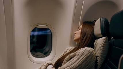 An airplane passenger is relaxing peacefully by the window, enjoying the scenic view during flight