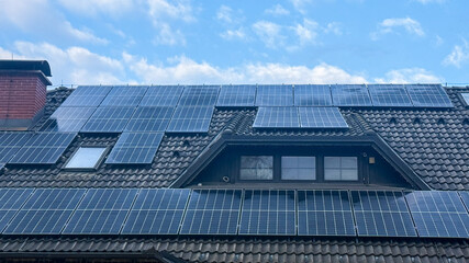 Fototapeta premium Solar panels on residential roof under blue sky, promoting renewable energy, eco-friendly technology, green living