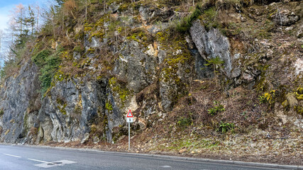 Rocky cliffside adjacent to rural road, ideal for nature exploration and outdoor adventure themes