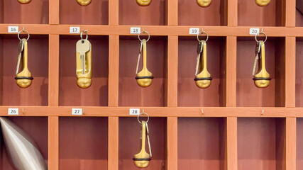 Hotel key rack with numbered gold keys, vintage hospitality concept, travel accommodation organization