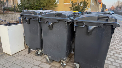 Row of black trash bins on urban street, waste management, environmental awareness, community...