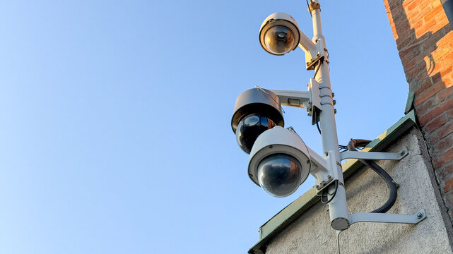 Surveillance cameras on urban building, security technology, public safety, modern monitoring system, blue sky