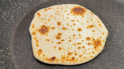 Close-up of a freshly cooked naan bread in a pan, Indian cuisine, traditional baking, homemade flatbread