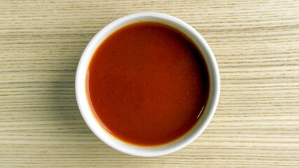 Tomato soup in a white bowl on wooden table, cozy comfort food, autumn dining
