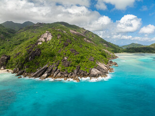 Crystal clear ocean meets rugged cliffs covered in greenery. Seychelles, Mahe.