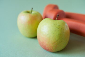 Apple and dumbbells on green background. Healthy eating concept.